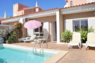 a pink umbrella sitting next to a swimming pool at Stylish well-equipped, private pool, close to amenities, free AC Wifi in Quarteira