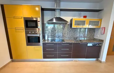 a kitchen with brown cabinets and a yellow wall at Pine Tree Seaside Apartments 500m to Beach in Albufeira