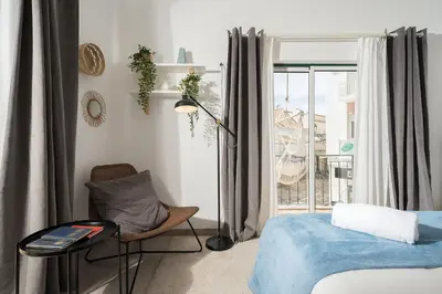 a bedroom with a bed and a chair and a window at Downtown Lux Apartment in Faro