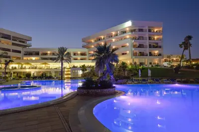 a large hotel with a large swimming pool at night at Alfagar Aparthotel in Albufeira