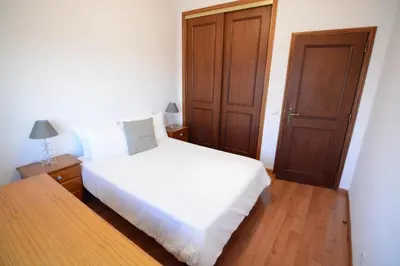 a bedroom with a white bed and a wooden door at Wonderful view in the city center in Faro