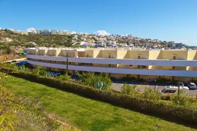 a large white building with a city in the background at Albufeira Prime Apartment in Albufeira