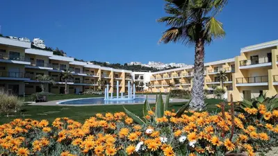 a large apartment building with a palm tree and flowers at Albufeira Prime Apartment in Albufeira