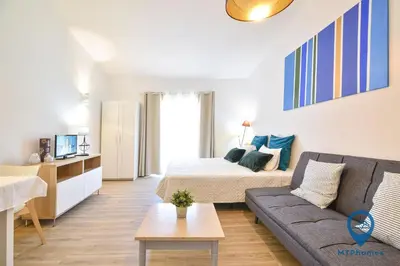 a bedroom with a large white bed and a couch at Estúdio Solar B by MTPhomes in Albufeira