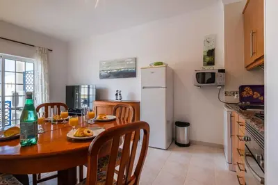 a kitchen with a table and a white refrigerator at Bosque São José by Algarneto in Albufeira