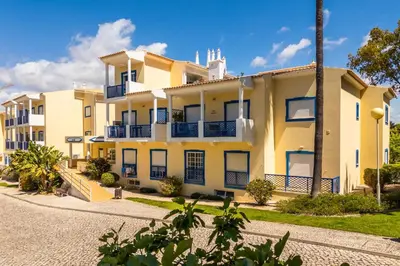an exterior view of a large yellow building at Bosque São José by Algarneto in Albufeira