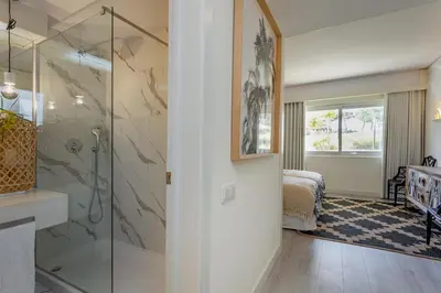 a bathroom with a walk in shower next to a bedroom at Victory Beach House in Quinta do Lago
