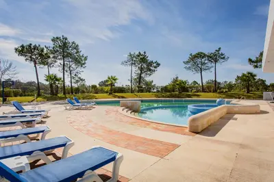 a swimming pool with blue lounge chairs and a pool at Victory Beach House in Quinta do Lago