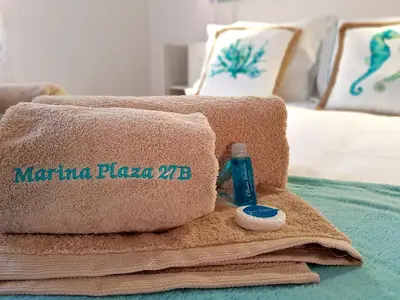 a pile of towels and a bottle on a bed at Marina Plaza 162 - Clever Details in Vilamoura