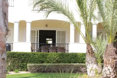 a white house with palm trees in front of it at Luxury 3 Bedroom Apartment on Gated Complex in Quarteira