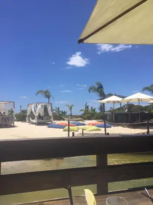 a beach with palm trees and umbrellas on it at Luxury 2 Bedroom Apartment with Private Garden in Almancil