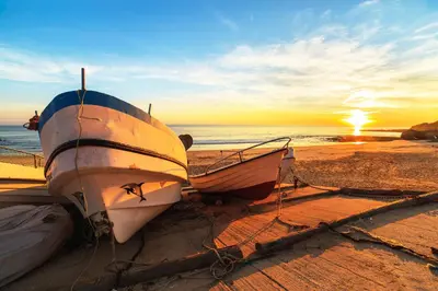 two boats sitting on the beach at sunset at Cool Grey Albufeira in Albufeira