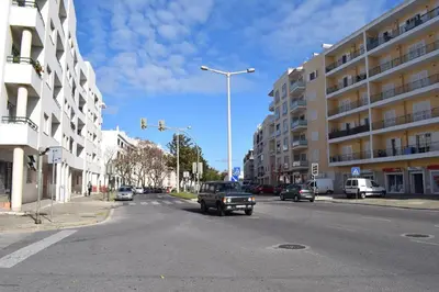 a car is driving down a city street with buildings at Quarteira Comfortable Apartment in Quarteira