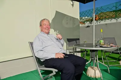 a man sitting in a chair holding a glass of wine at Guest House Sao Filipe in Faro