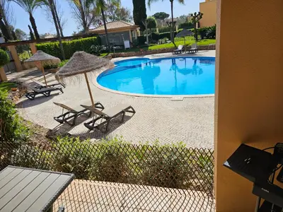 a swimming pool with two chairs and umbrellas at Citadela I, Golfe, Pool and Falesia Beach in Vilamoura