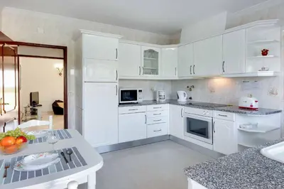 a white kitchen with white cabinets and a table at Villa Licinia in Guia