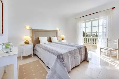 a white bedroom with a bed and a large window at Villa Licinia in Guia