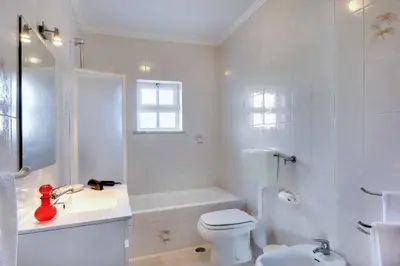 a white bathroom with a toilet and a bath tub at Villa Licinia in Guia