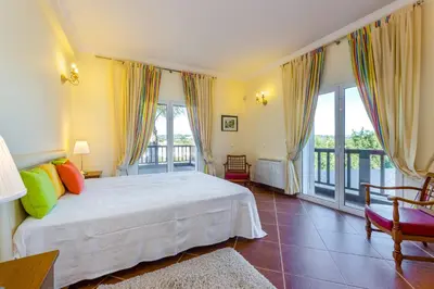 a bedroom with a white bed and a balcony at Villa Amarela in Boliqueime