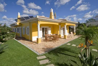 a yellow house with a patio and a yard at Villa Amarela in Boliqueime