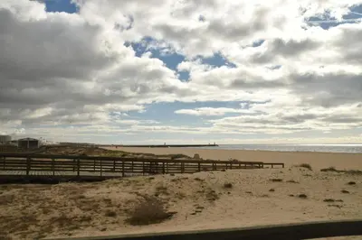 a beach with a wooden fence and the ocean at Amora Villa - Vilamoura in Vilamoura