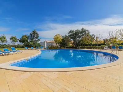 a large swimming pool with blue chairs in a yard at Apartment Monte da Eira by Interhome in Brejos