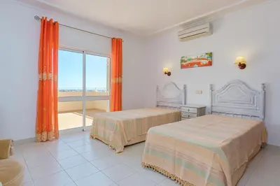a bedroom with two beds and a large window at Villa Mirante in Albufeira