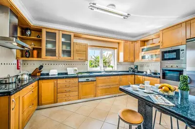 a large kitchen with wooden cabinets and a table at Villa Luana in Olhos de Água