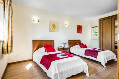 two beds in a room with red pillows at Villa Luana in Olhos de Água