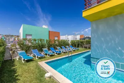 a swimming pool with blue chairs next to a building at Villa 14 Marina de Albufeira in Albufeira
