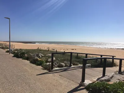 a sandy beach with people walking on the beach at Apt 2 Quartos, BBQ, AC, Varanda, Prestige For Home in Quarteira