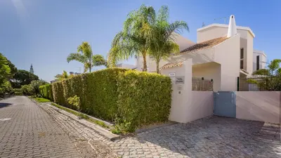 a white house with a hedge next to a street at Villa Oriente - Greice Homes in Vilamoura