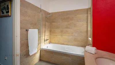 a bathroom with a tub and a red wall at Villa Oriente - Greice Homes in Vilamoura