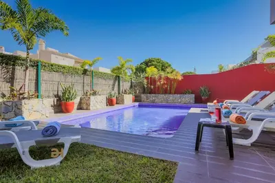 a swimming pool in a backyard with chairs and a table at Villa Oriente - Greice Homes in Vilamoura
