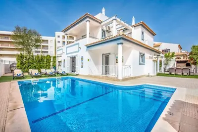 a villa with a swimming pool in front of a house at Villa Jomar in Guia