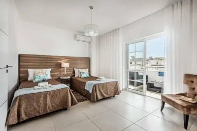 a bedroom with two beds and a chair and a window at Villa Jomar in Guia