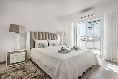 a white bedroom with a large bed and a window at Villa Jomar in Guia