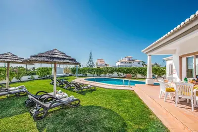 a yard with chairs and a swimming pool and a house at Villa Damara in Albufeira
