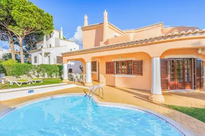 a villa with a swimming pool in front of a house at Villa Ponderosa in Quarteira