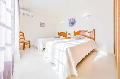 two beds in a room with white walls at Villa Ponderosa in Quarteira