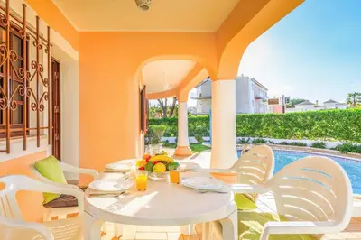 a patio with a table and chairs and a pool at Villa Ponderosa in Quarteira