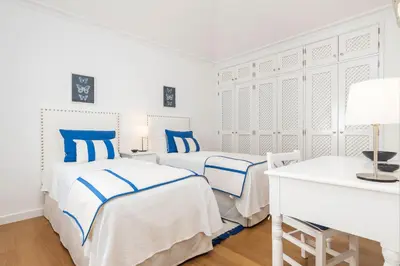 two beds in a white room with blue pillows at Encosta Do Lago Resort Club in Quinta do Lago