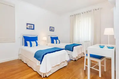 two beds in a white room with blue accents at Encosta Do Lago Resort Club in Quinta do Lago