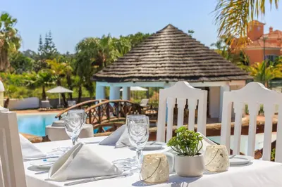 a table with white chairs and a table with glasses at Encosta Do Lago Resort Club in Quinta do Lago
