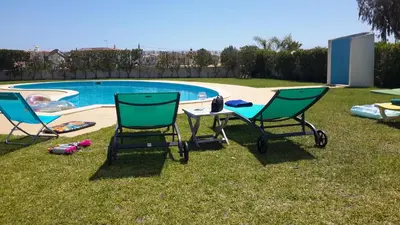 two chairs and a table next to a swimming pool at Villas Sol e Poesia in Albufeira