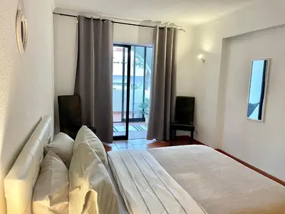a bedroom with a bed and a sliding glass door at Apartamento bem localizado in Albufeira
