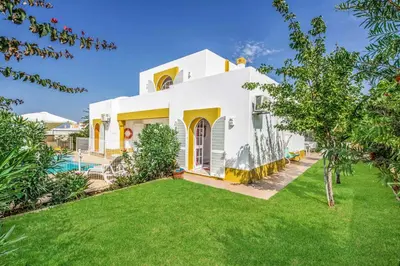 a white house with a yard and a pool at Villa Arines in Albufeira