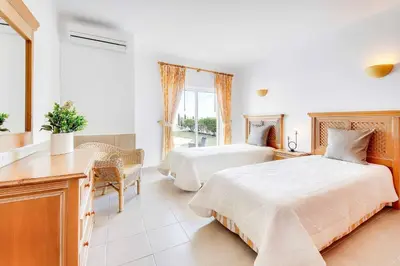 a bedroom with two beds and a desk and a window at Villa Beatrice in Albufeira