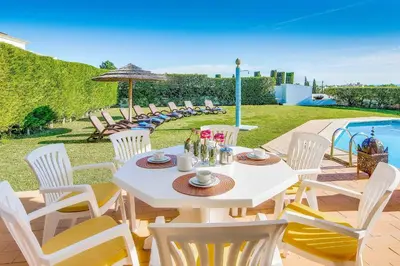 a house with a yard with chairs and a swimming pool at Villa Beatrice in Albufeira