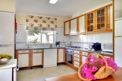 a kitchen with wooden cabinets and a basket of flowers at Villa Adele in Albufeira